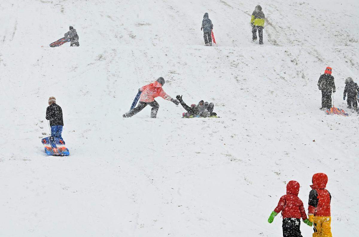 As they complete their run down a snow covered hill children slap hands, center, at Veterans Park in Charlotte on Saturday, January 31.