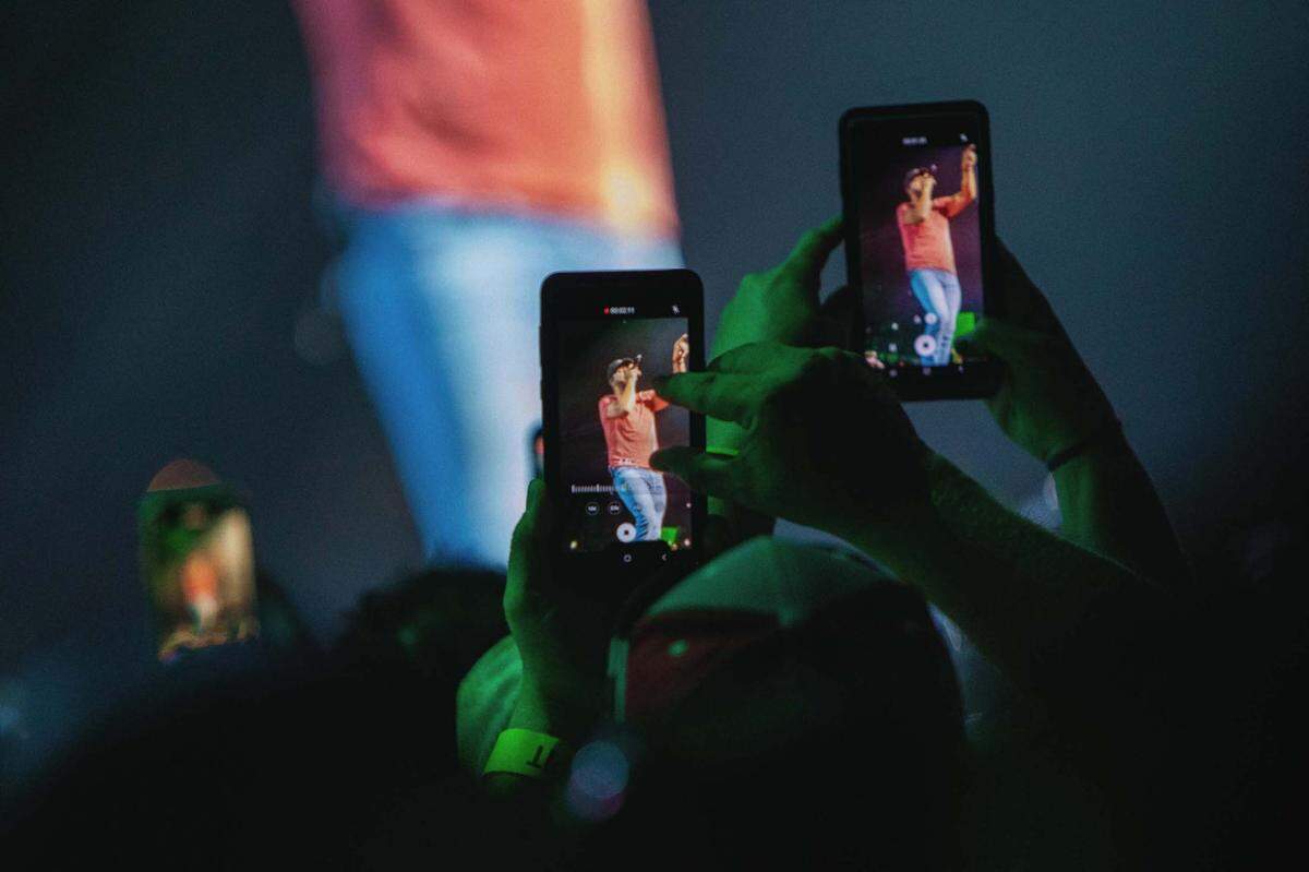 Fans capture moments from Friday night’s concert on their cellphones.