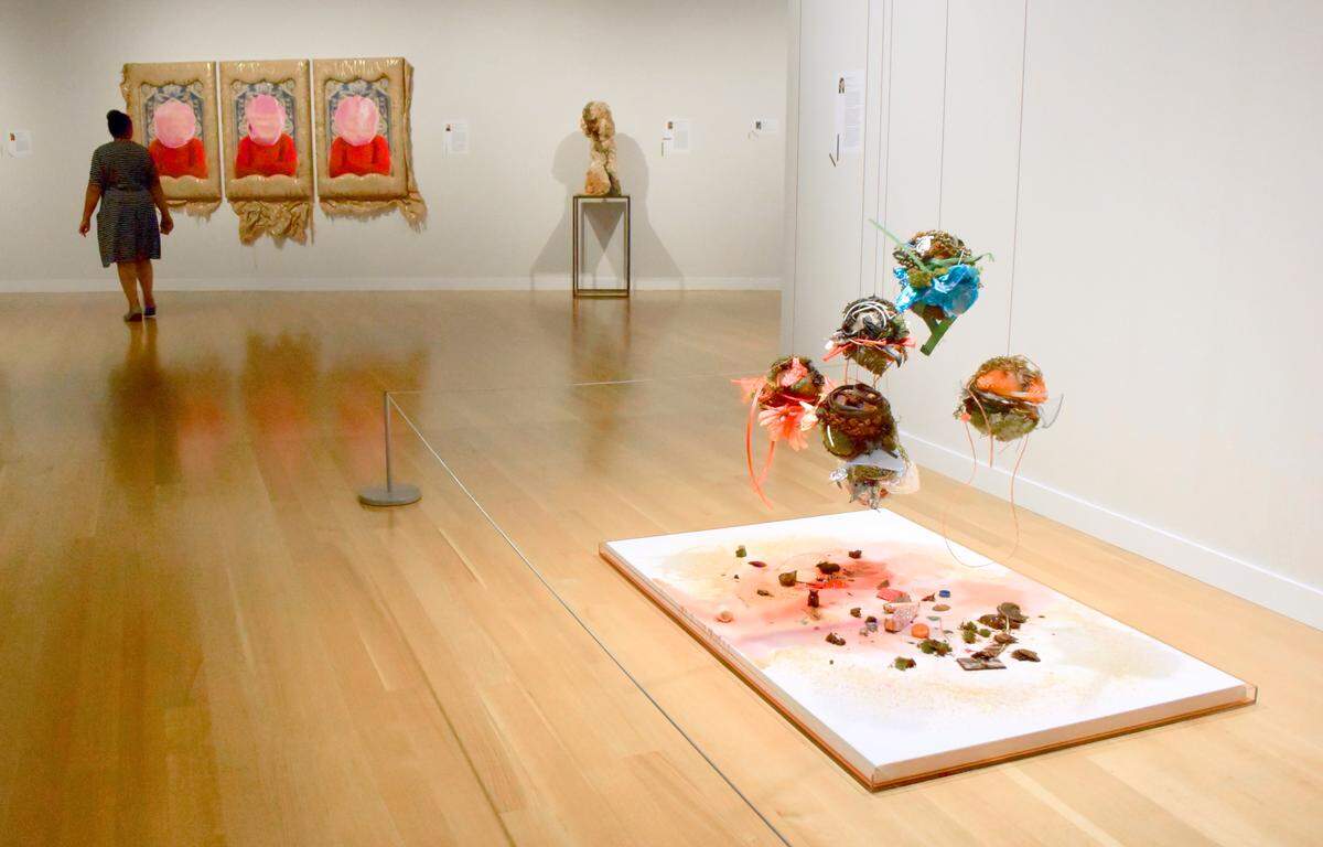 “Wayside: Charlotte” (above, right) is part of a series done by Davidson artist Katie St. Clair. She collects, freezes and melts debris from one location in an attempt to tell the story of a place. The ice spheres, which hang from the ceiling above a primed white canvas, contain debris St. Clair collected from around the city. The colored water slowly drips onto the canvas, creating an abstract watercolor.