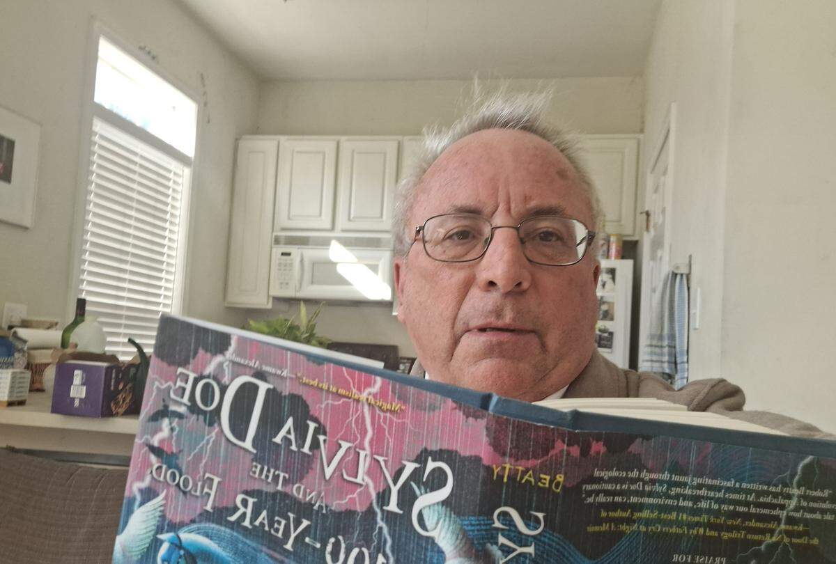 Joe Marusak holds up a copy of “Sylvia Doe and the 100-year Flood” by Robert Beatty.