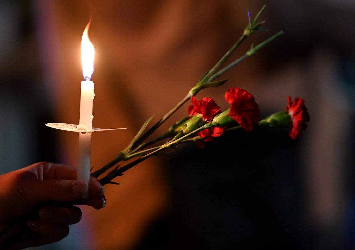 A community member holds a candle and carnations during a candlelight vigil for Iryna Zarutska  in September 2025.
