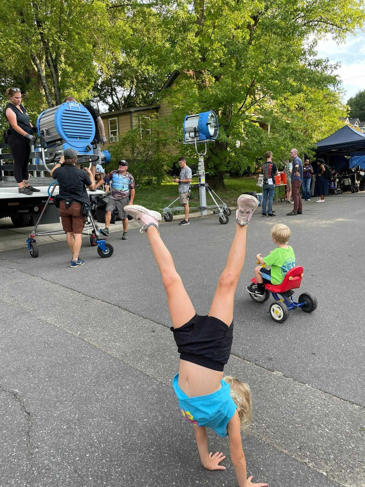 Hannah Rose Tosco, 8, does cartwheels as Harry Tosco, 6, rides a tricycle among set equipment for the filming of Please Don’t Destroy: The Treasure of Foggy Mountain.