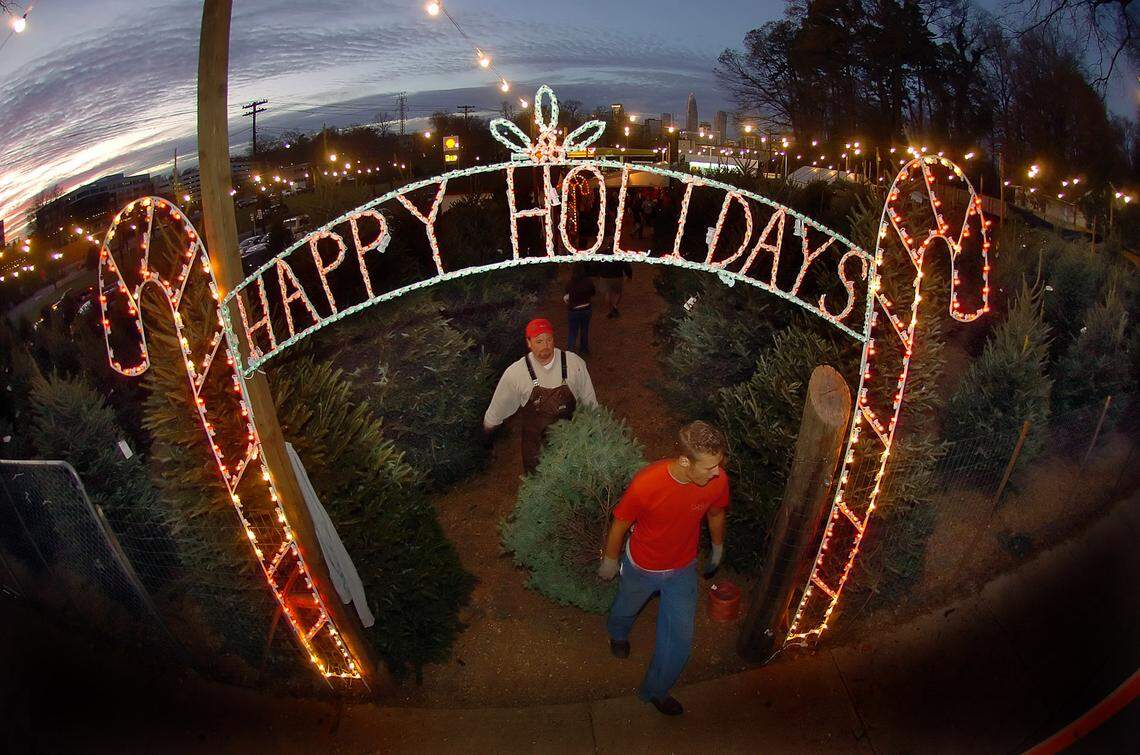 Kevin Pressley (back) and Mitch Johnson carry a tree from Simpson Family Christmas Trees lot, which has operated on Kings Drive since 1941. Co-owner David Simpson died last week from COVID-19.
