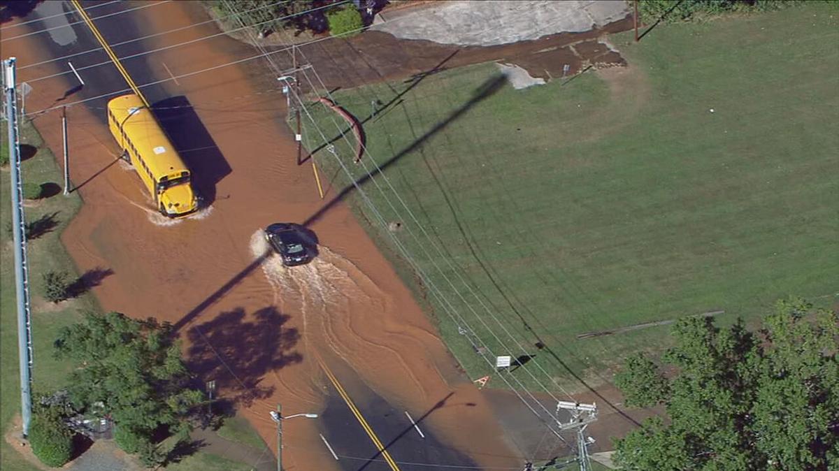 This image from WSOC’s helicopter shows a school bus and another vehicle trek across a flooded road in west Charlotte on Tuesday, September 27, 2022.