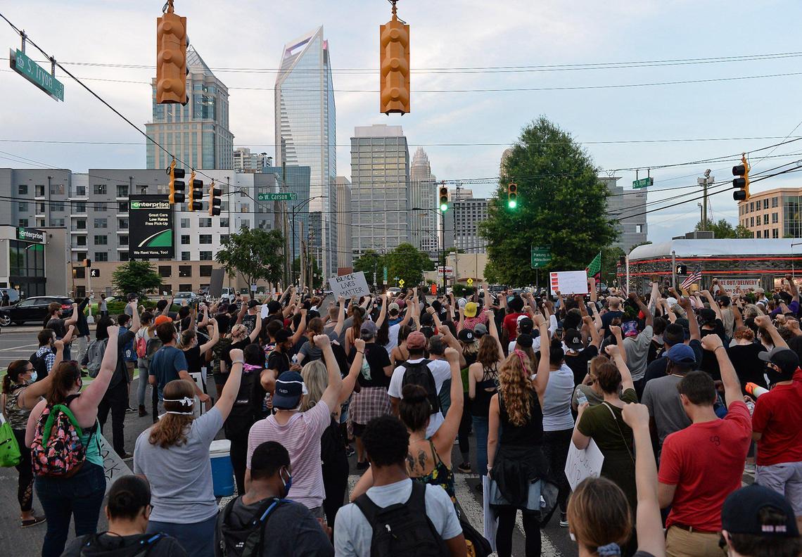 Demonstrators raise their right fists into the air while standing in the intersection of South Tryon St. and Carson Ave. in uptown Charlotte, NC on Friday, June 5, 2020. Demonstrators have been marching throughout Charlotte for eight days in response to the killing of George Floyd, a black man who was killed on Monday, May 25, 2020 by a Minneapolis, MN police officer.