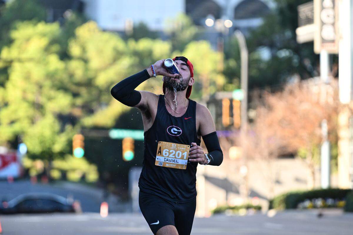 Daniel Navarro drinks a beer while competing at the 20th annual Novant Health Charlotte Marathon on Saturday, Nov. 16, 2024, in Charlotte