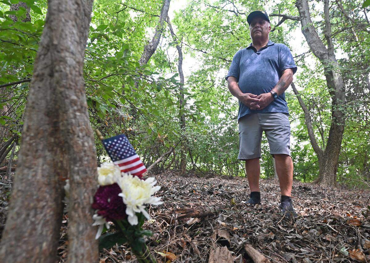 Louie Pinheiro stands near the small bouquet of flowers and American flags he left near the site on Aug. 30, 2024, where he brother John died in 1974. John Pinheiro was one of 72 people who died in the crash of Eastern Flight 212 on September 11, 1974. His brother Louie has visited the site four times and said each time it makes him feel closer to John.