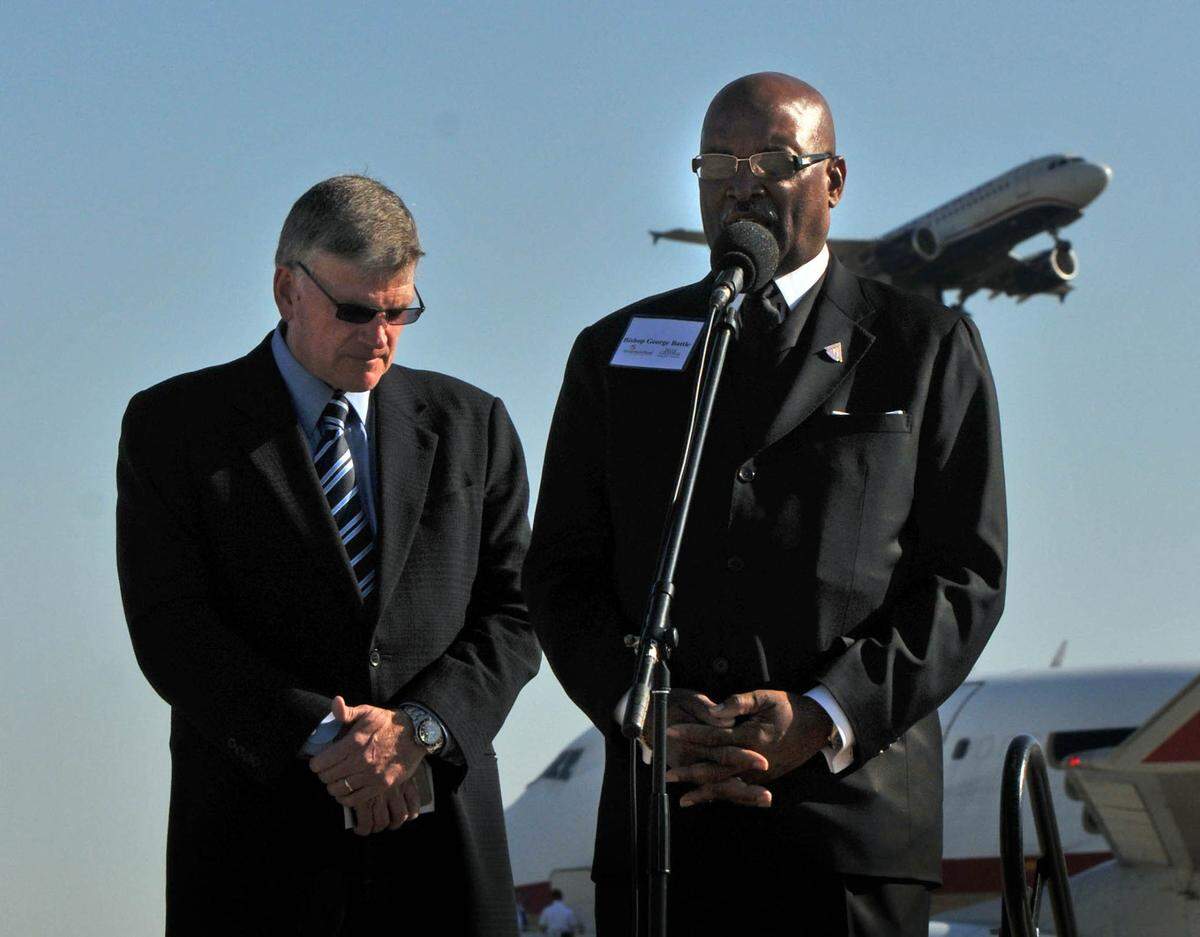 Franklin Graham, left, bows his head as Bishop George Battle leads a prayer at Charlotte Douglas International Airport in 2011. Samaritan’s Purse was sending 90 tons of relief supplies to Japan.
