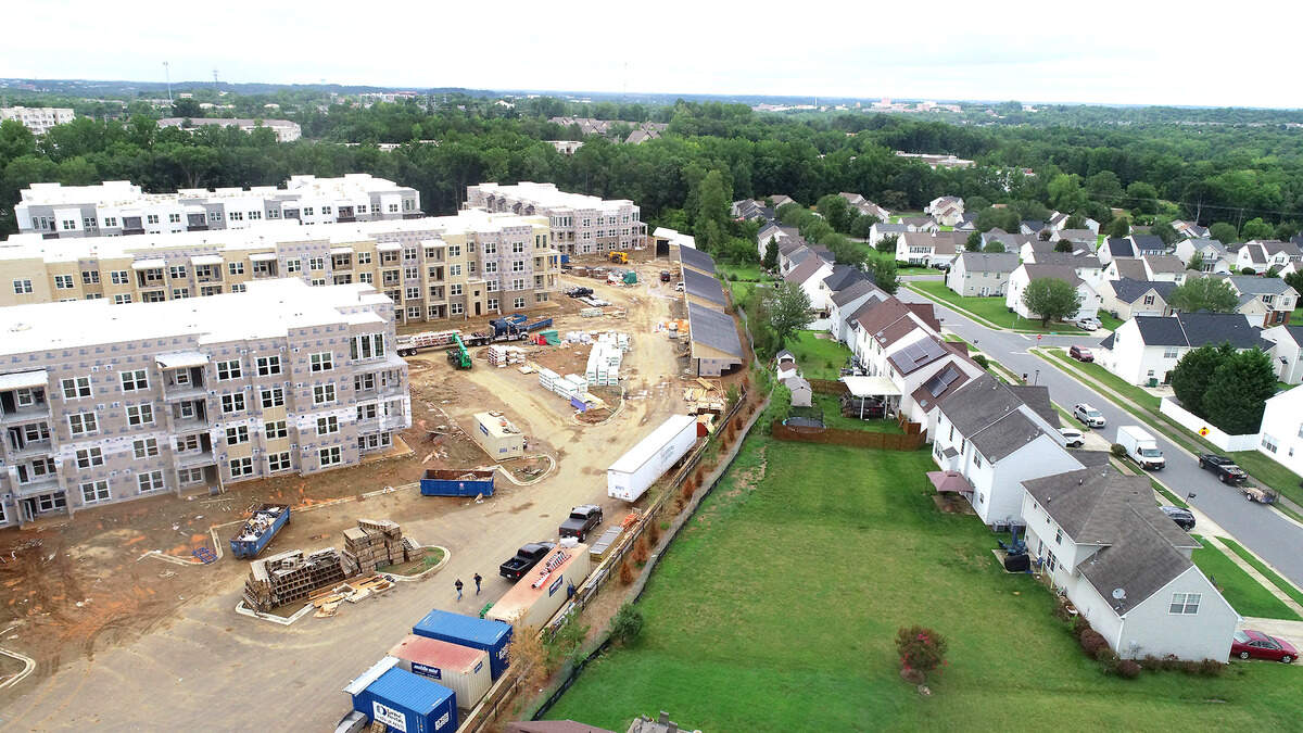 Fencing separates the Tapestry University City development from the homes in Rocky River Village in the University City area of Charlotte, on Thursday, July 8, 2021. Tapestry University City is a luxury apartment community.