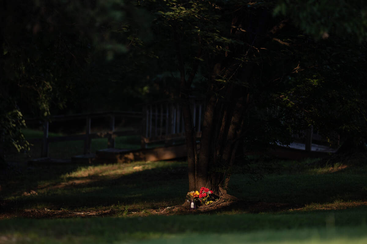 Fabric roses stand at the base of the tree where Juliana Nzita was found hanging in a North Charlotte churchyard.