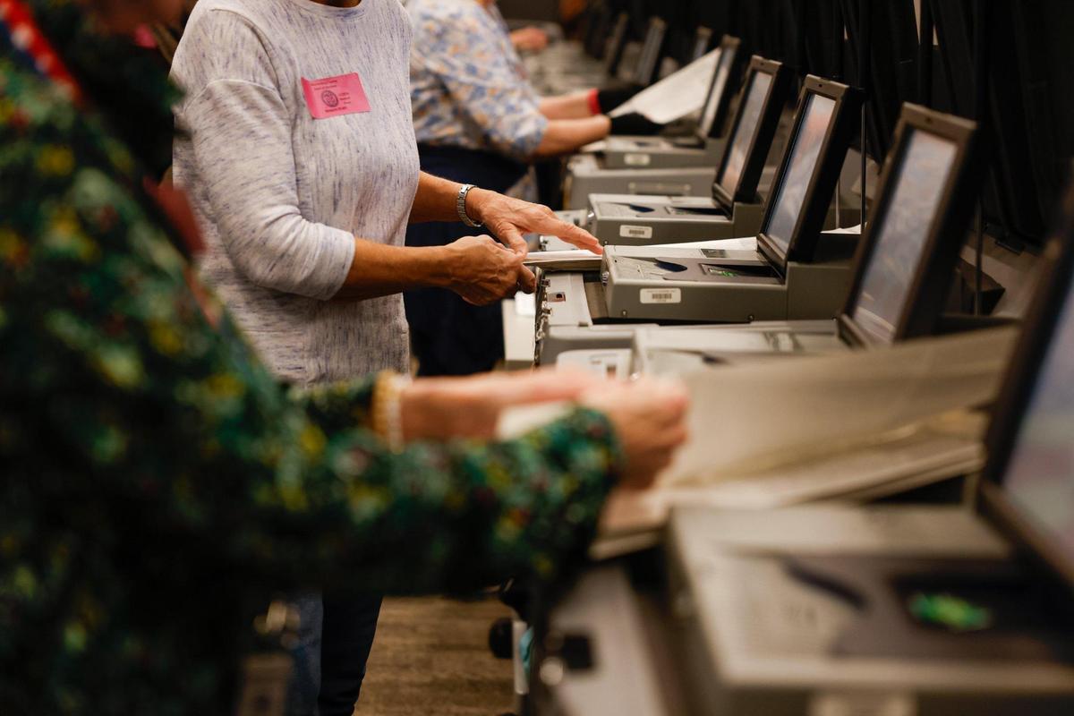 Volunteers feed ballots into ballot machines.