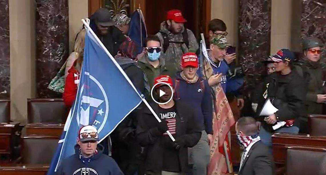 Chris Carnell of Cary, (center and wearing a red cap) was charged in connection with the Capitol riot. His companion, David Bowman of Raleigh, also charged, is center left in blue mask.