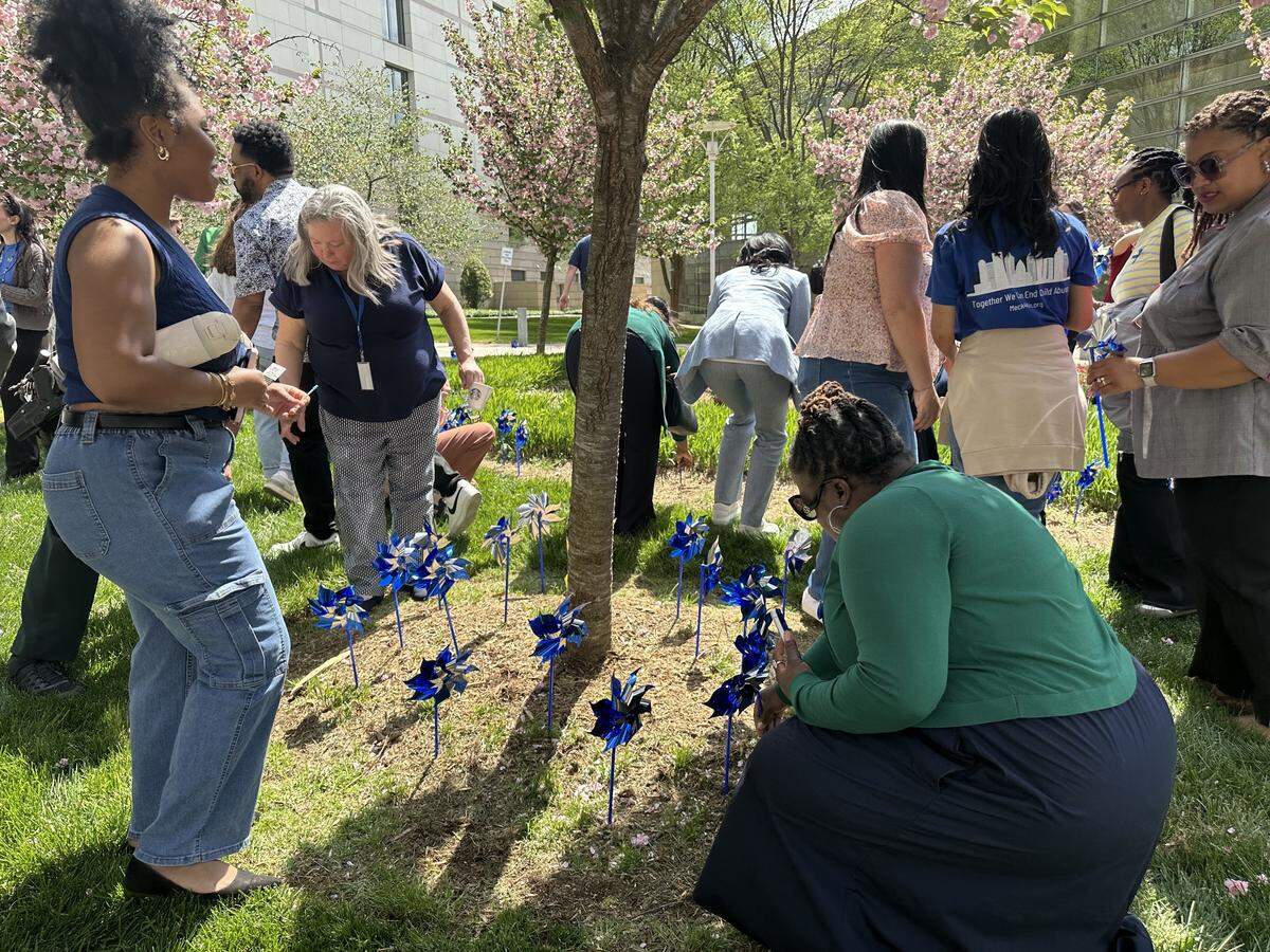 Attendees plant blue pinwheels around a tree near the Mecklenburg County Courthouse. The blue pinwheel is a national symbol of child abuse prevention awareness, a speaker said.