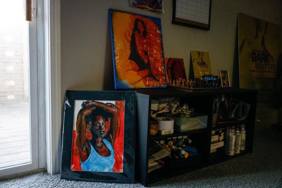 Art in Dasia Hood’s home includes works by Kevin Harris (on the floor in blue and red; Hood is the model) and the one on the shelf is by Dru Swan. Swan’s artwork is part of “[red]” at Lorem Ipsum, and is on display there through March 5.