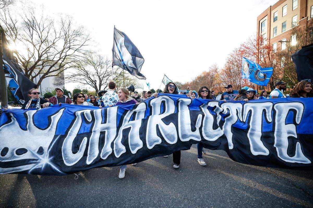 The banner for the fan march from the tailgate to the stadium is carried entirely by women before Charlotte FC’s match against the Columbus Crew on Saturday, March 23, 2024.