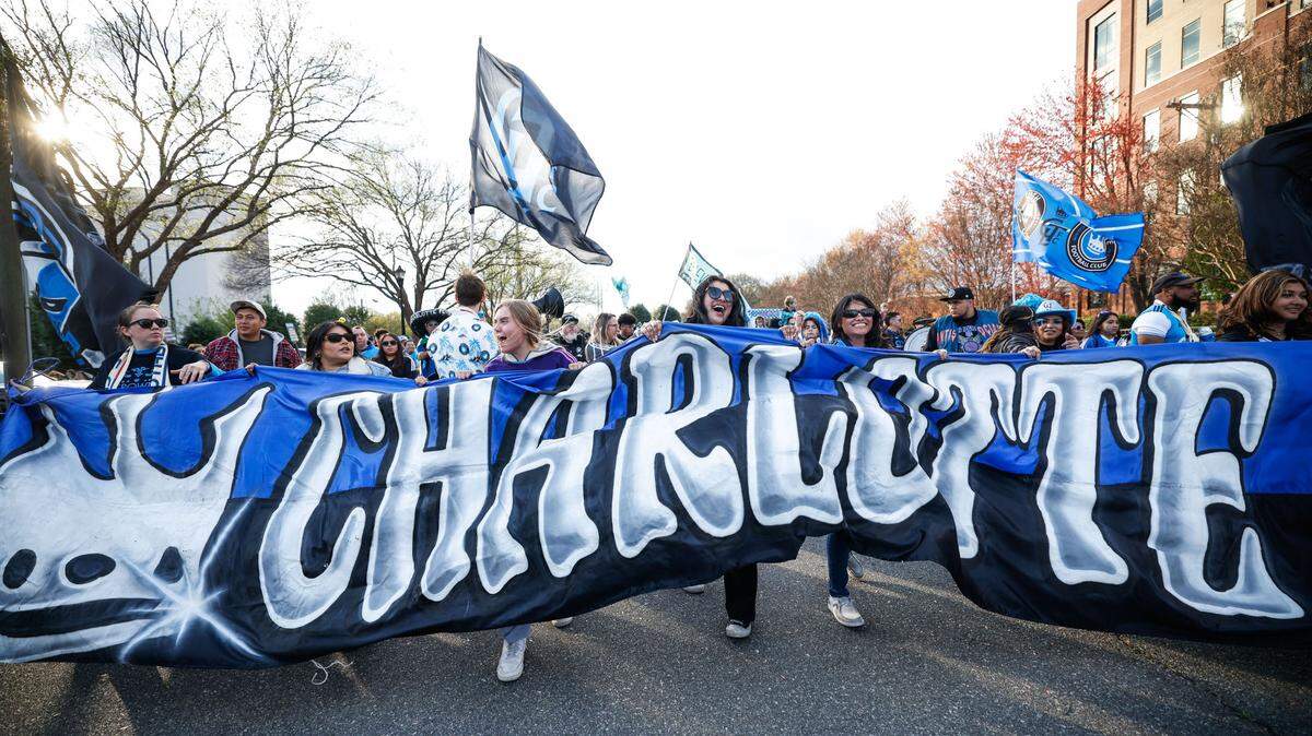 The banner for the fan march from the tailgate to the stadium is carried entirely by women before Charlotte FC’s match against the Columbus Crew on Saturday, March 23, 2024.