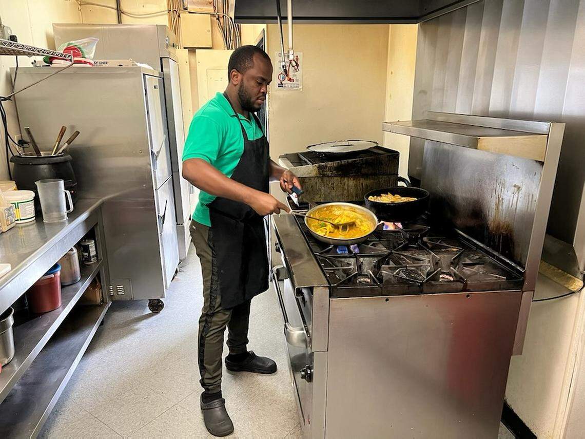Fidel Clarke works on a shrimp curry meal, one of the options available at his new takeout restaurant. He learned to cook in his mother’s kitchen in Jamaica.