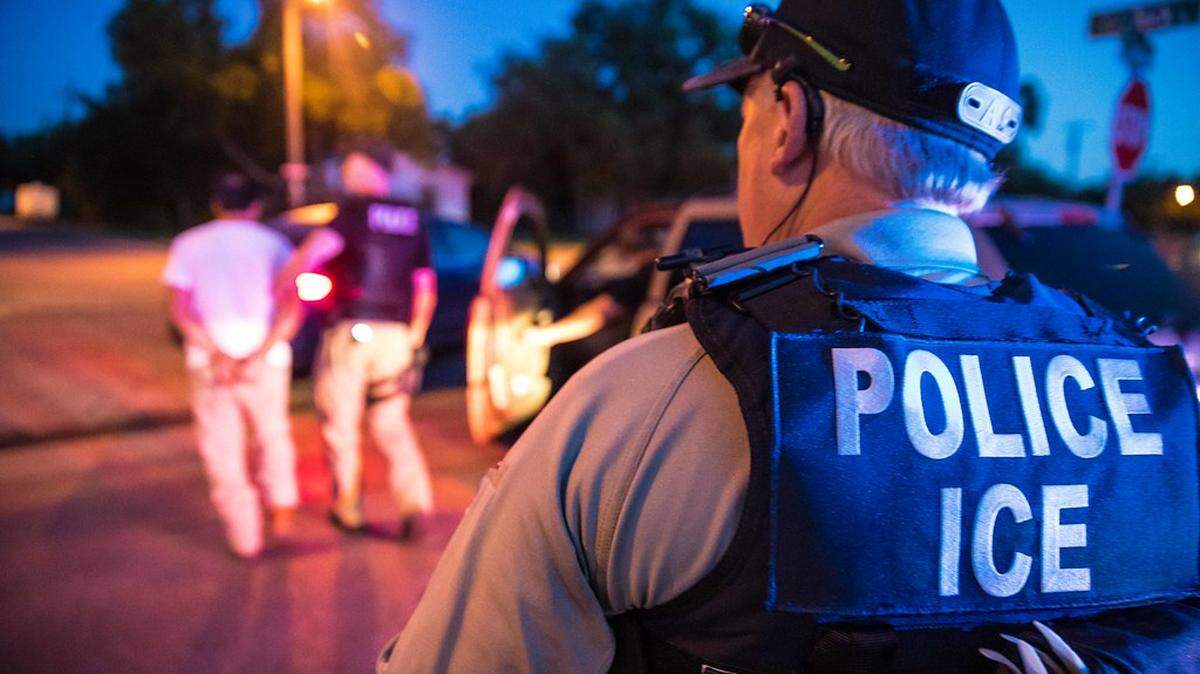 A U.S. Immigration and Customs Enforcement officer observes a detainment.