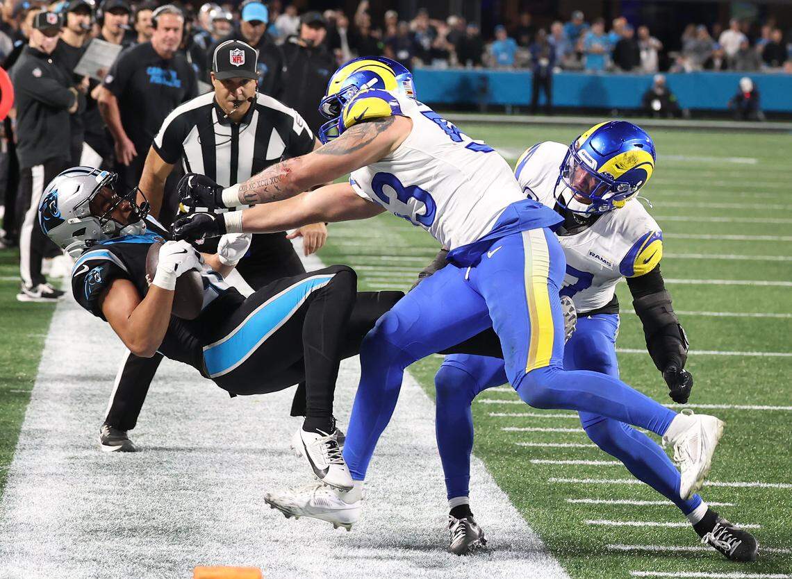 Carolina Panthers wide receiver Jalen Coker, left, is pushed out of bounds by Los Angeles Rams linebacker Nate Landman, center, following a pass reception at Bank of America Stadium on Saturday, January 10, 2026. Landman was penalized on the play. The Rams defeated the Panthers 34-31.