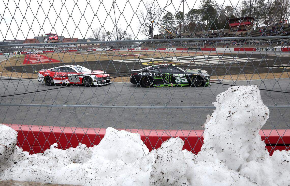 Snow fills the area behind a safer barrier as NASCAR drivers Ryan Preece, left and Riley Herbst, right, drive into Turn 1 at Bowman Gray Stadium in Winston-Salem on Wednesday, Feb. 4, 2026. The stadium is hosting the Cookout Clash.
