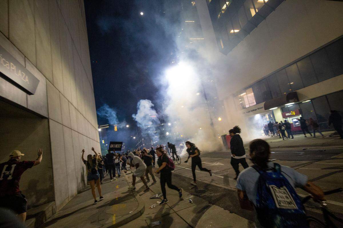 Protesters scramble on 4th Street as police fire chemical agents on either side of the protesters in uptown Charlotte, NC on Tuesday, June 2, 2020.