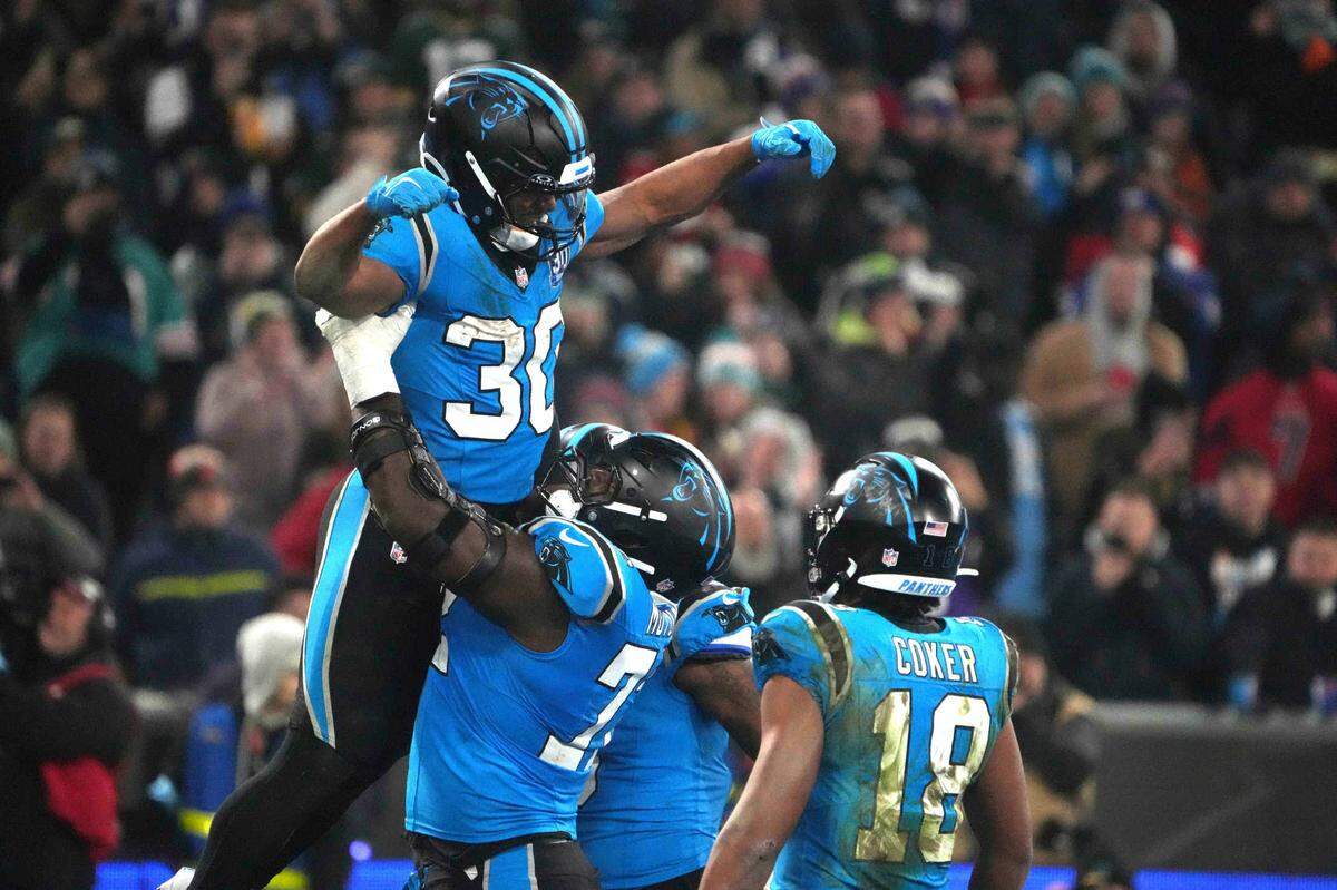 Carolina Panthers running back Chuba Hubbard (30) celebrates with offensive tackle Taylor Moton (72) and wide receiver Jalen Coker (18) after scoring on a 1-yard touchdown run against the New York Giants in Sunday’s second half during the 2024 NFL Munich Game at Allianz Arena.