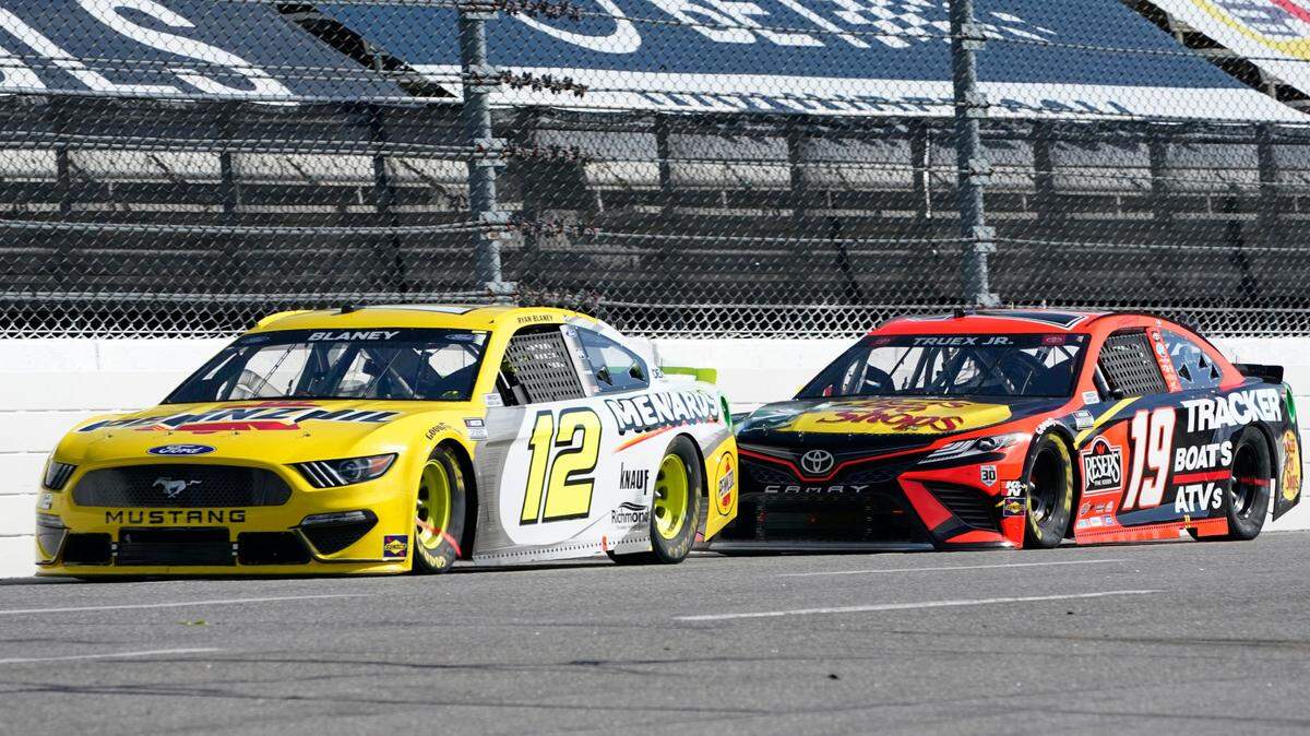 Ryan Blaney (12) and Martin Truex Jr. (19) approach the third turn during a NASCAR Cup Series auto race at Martinsville Speedway in Martinsville, Va., Sunday, April 11, 2021. (AP Photo/Steve Helber)