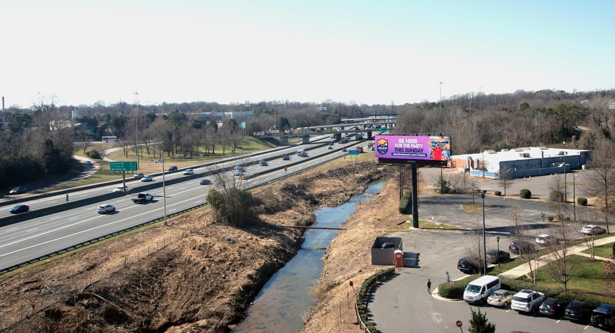 Once filled with vegetation, this creek bank near an Interstate 77 billboard has been clear-cut because of a 2024 law.
