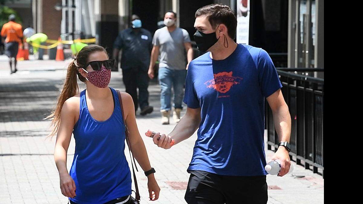 Businesses are urged by North Carolina Gov. Roy Cooper to have employees show proof of vaccination, health screenings and urge mask compliant with the Centers for Disease Control’s latest recommendation. Shown, pedestrians wearing masks in uptown Charlotte.