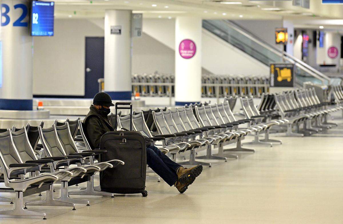 A lone traveler sits in the baggage claim area at Charlotte Douglas International Airport on Sunday, January 16, 2022 as a wintry mix blanketed the area. 