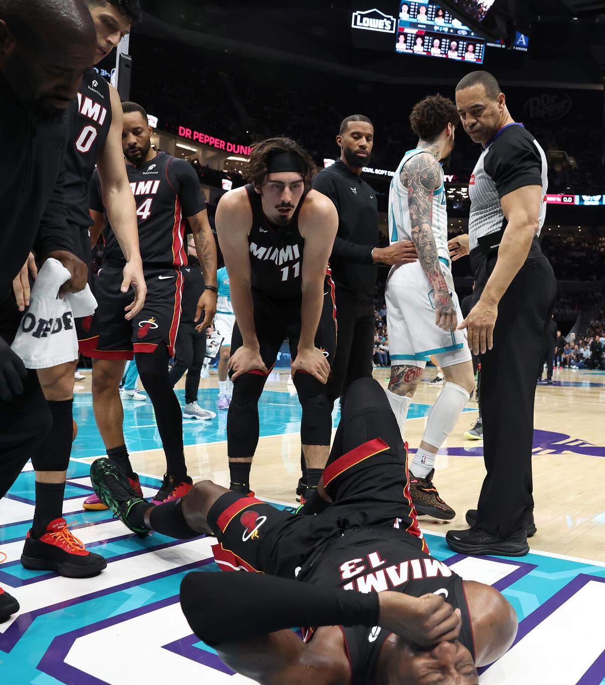 Charlotte Hornets guard LaMelo Ball, center/right, is led away by head coach Charles Lee, center/left, as Miami Heat forward/center Bam Adebayo, bottom, lies on the floor injured Tuesday night at Spectrum Center.