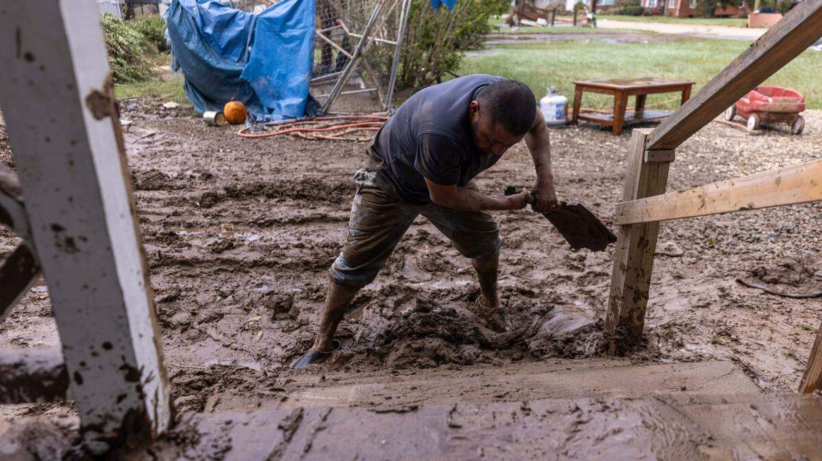 North Carolina residents like Tomas Quiroz, shown Sept. 28, 2024, shoveling mud from his porch steps in Clyde, are urged by federal and state environmental agencies to wear PPE during cleanup.