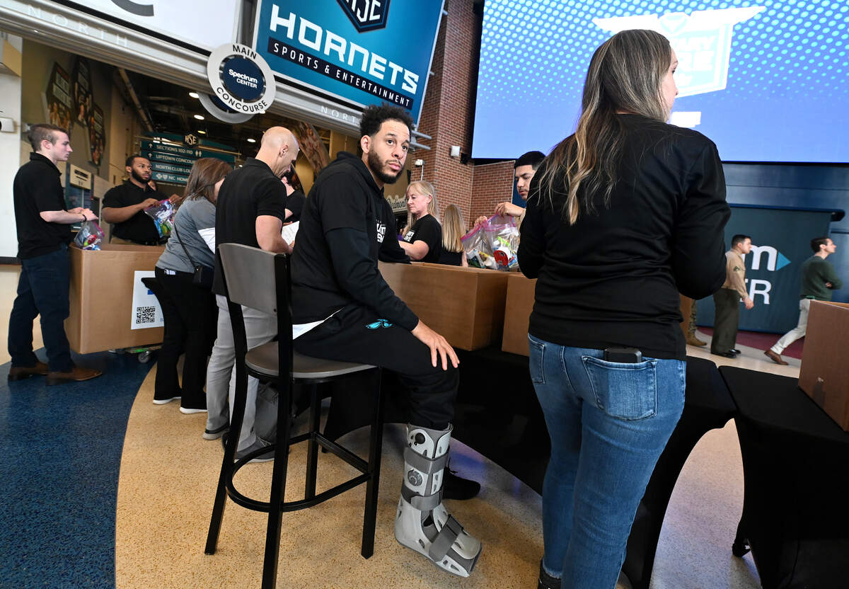 Charlotte Hornets guard Seth Curry, center, wears a walking boot on his right leg during the team and Novant Health’s Military Care event at Spectrum Center on Monday, March 4, 2024.