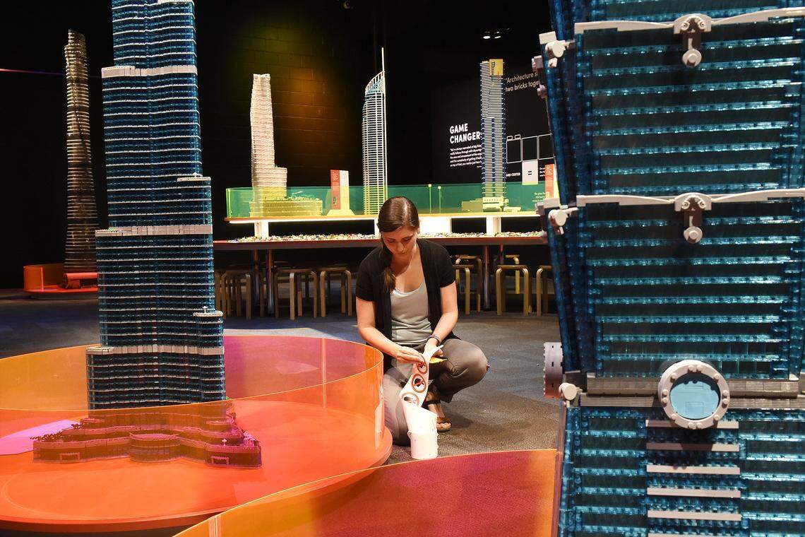 Althea Holenko, a graphic designer for Discovery Place, places Do Not Touch stickers on each of the 20 skyscrapers made from Lego bricks in the Towers of Tomorrow exhibit.
