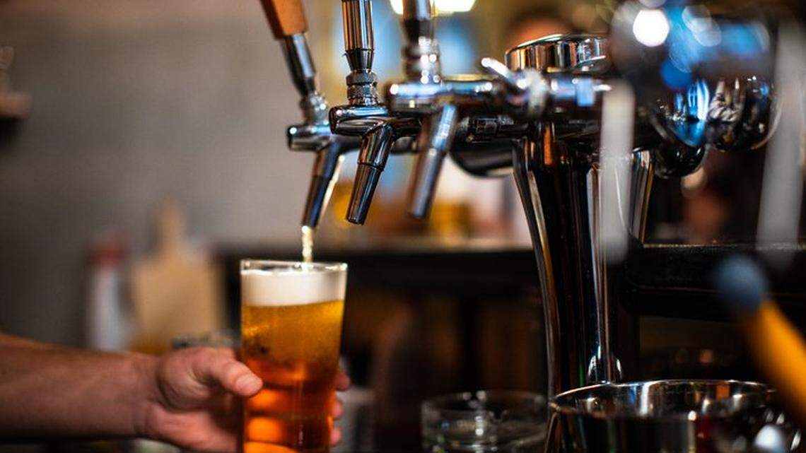 A bartender pours a glass of beer for a customer.