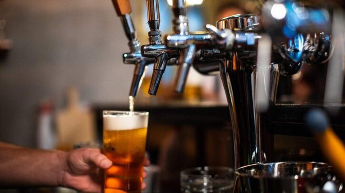 A bartender pours a glass of beer for a customer.