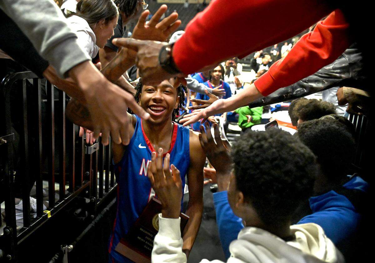 North Meck’s Isaiah Evans, center, is all smiles as fans lean over the railing to congratulate him and the rest of the team following their 65-61 victory in the 4A Regional Championship game on Thursday, March 14, 2024 at Lawrence Joel Veterans Memorial Coliseum in Winston-Salem, NC. North Meck defeated Lake Norman to advance to the NCHSAA final Saturday.
