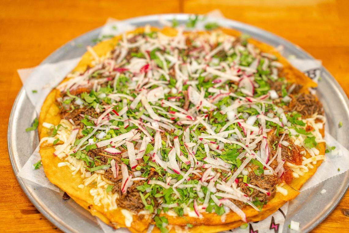 The Birria Pizza at Birritaco is a double layer flour tortilla crust with Chihuahua cheese, Mexican marinara, onions, cilantro, radishes and birria beef with up to four consommés.