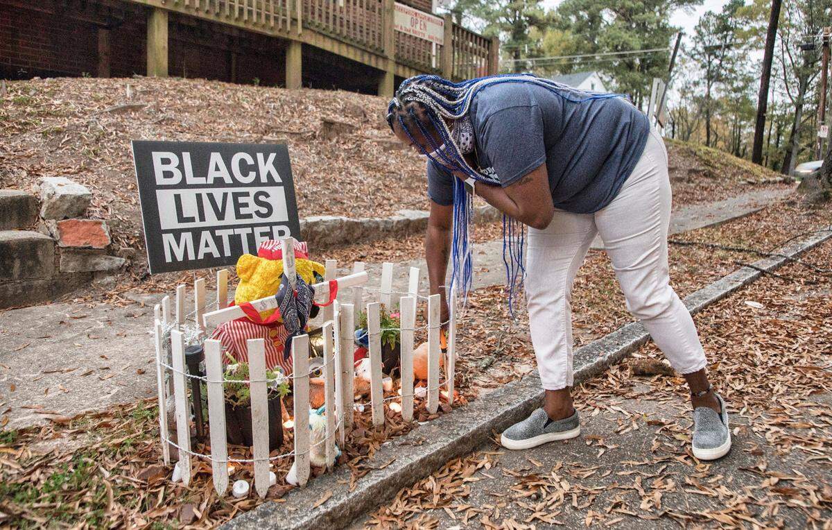 Lavern Lucier lights candles on November 9, 2020 at a memorial she created for her son, Syncere Burrell. Burrell was shot and killed where the memorial sits, near the corner of Lincoln St. and Linwood Ave. in Durham, N.C. on August 10, 2020.