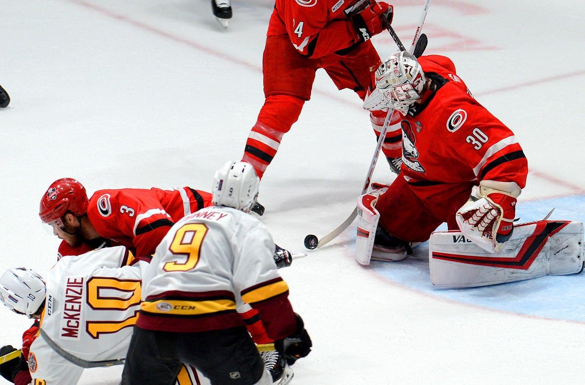 Charlotte Checkers goalie Alex Nedeljkovic, right, stops a shot on goal during Game 1 of the AHL Calder Cup Finals against the Chicago Wolves at Bojangles’ Coliseum on Saturday.