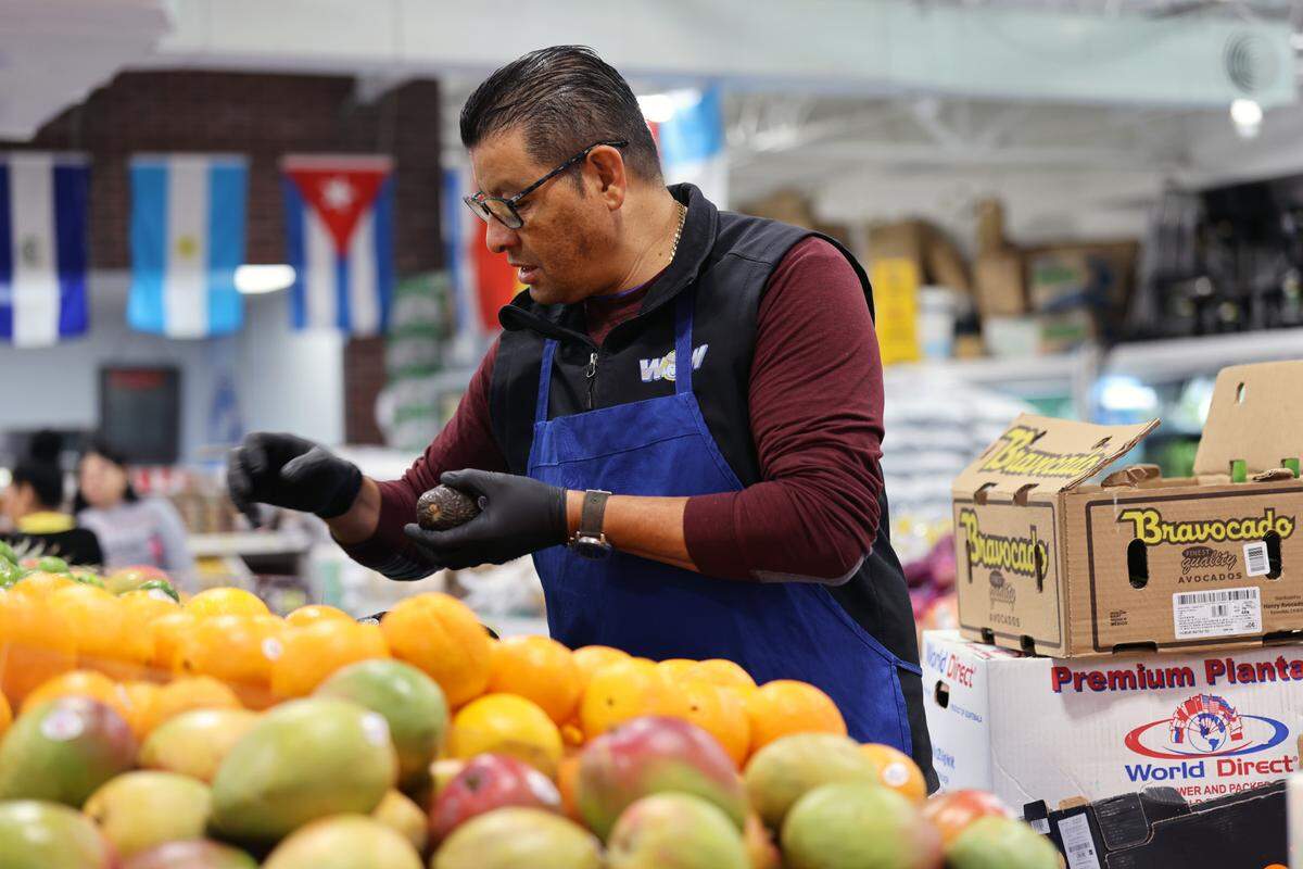 Juan Hernandez handles produce at the grocery store, Wow Supermarket, as the store faces rising costs of mangoes, limes and avocados due to international tariffs on Tuesday, May 20, 2025.