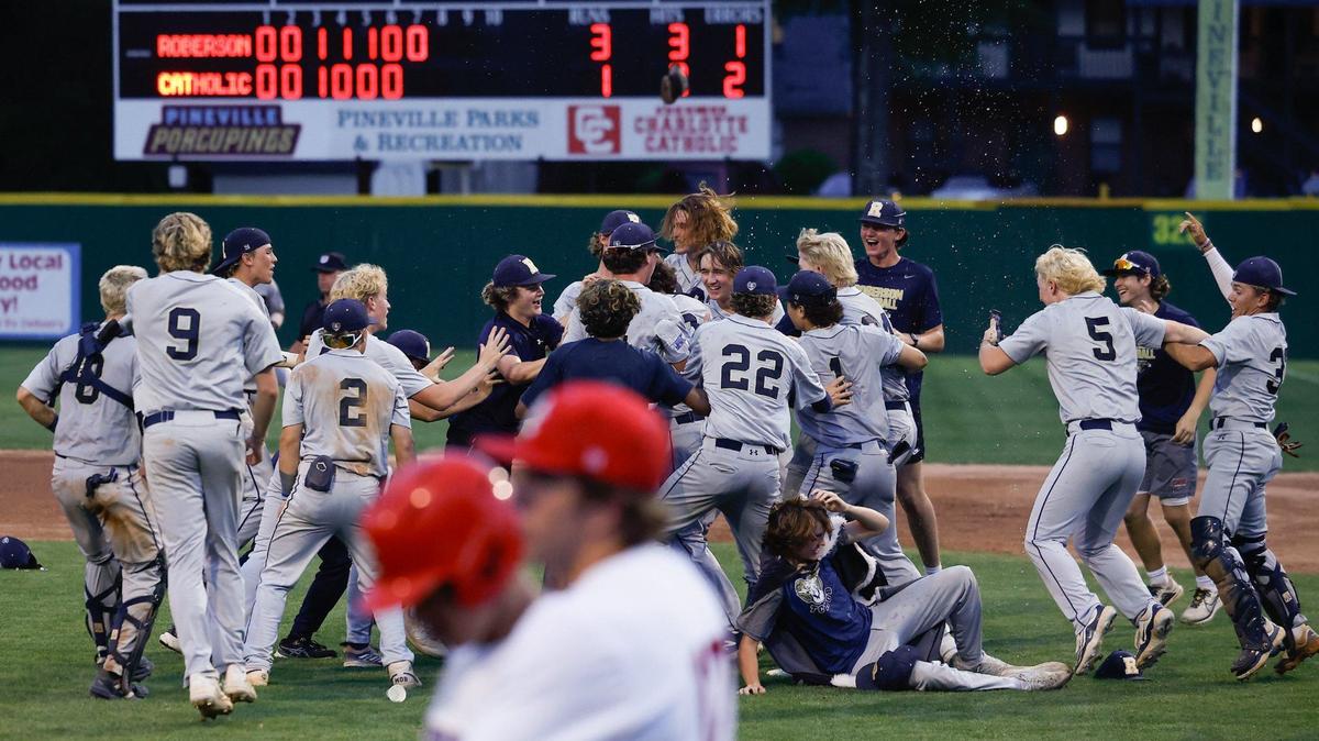TC Roberson’s players celebrate on the field after defeating Charlotte Catholic, 3-1, in the NCHSAA Western Regional championship baseball series against TC Roberson at Jack Hughes Park in Pineville on Thursday, May 23, 2024. Roberson advances to the state championship.