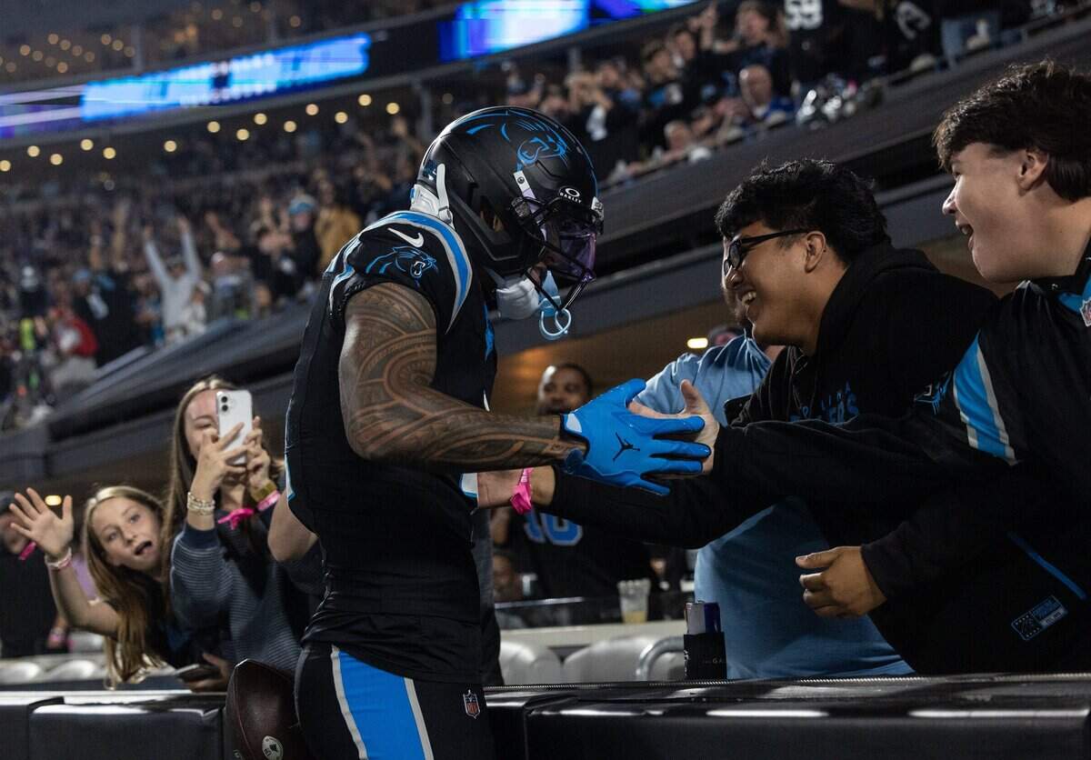 Panthers wide receiver Tetairoa McMillan, left, celebrates his touchdown with two fans, Kevin Gamez, 17, center, and Owen Murray, 17, far right during the game against the Lions at Bank of America Stadium in Charlotte on Sunday, October 4, 2026.
