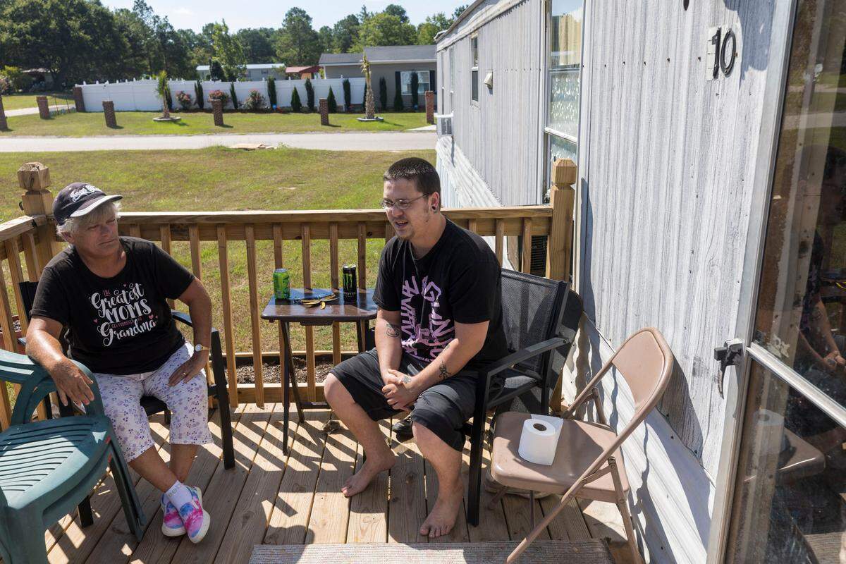 Preston Fritz talks with his mother, Sherry Fritz, on the porch of their home near Lumber Bridge. Preston keeps a roll of tissue close by to deal with a constantly runny nose - a problem that he attributes to the particles that drift from 48 massive chicken barns nearby.