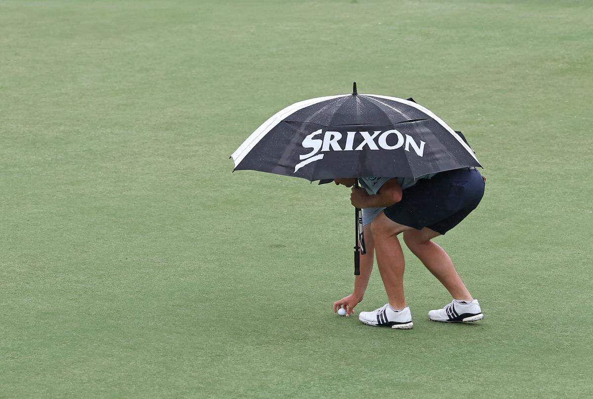 Golfer Sepp Straka uses an umbrella to shield himself from the rain as he positions his ball on the 15th green during the Truist Championship Pro-Am at Quail Hollow Club in Charlotte, NC on Wednesday, May 6, 2026. 