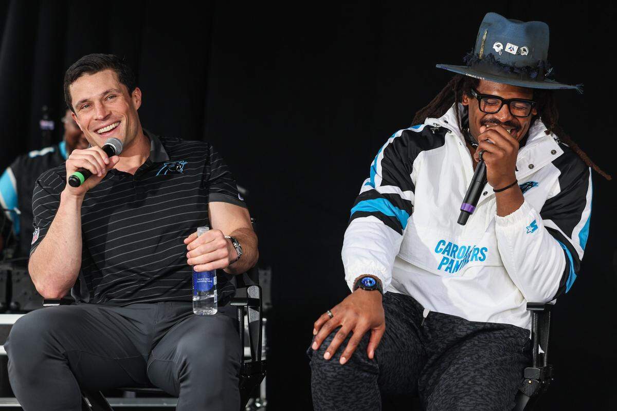 Luke Kuechly, left, joins Cam Newton during the live airing of the podcast “4th & 1” at the Roaring Riot tailgate before the Wild Card playoff game in Charlotte on Saturday, Jan. 10, 2026.