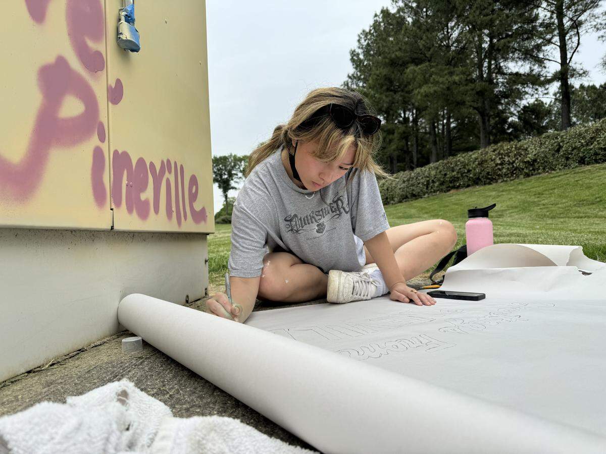 Art student Sophie Romine prepares a stencil for a utility box at Pineville Lake Park.