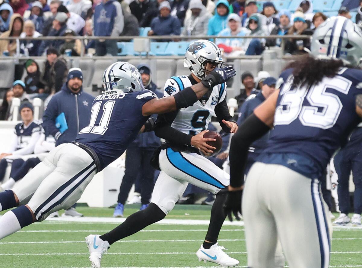Carolina’s Bryce Young carries the ball as Dallas’s Michah Parsons tries to tackle him Sunday in Charlotte.