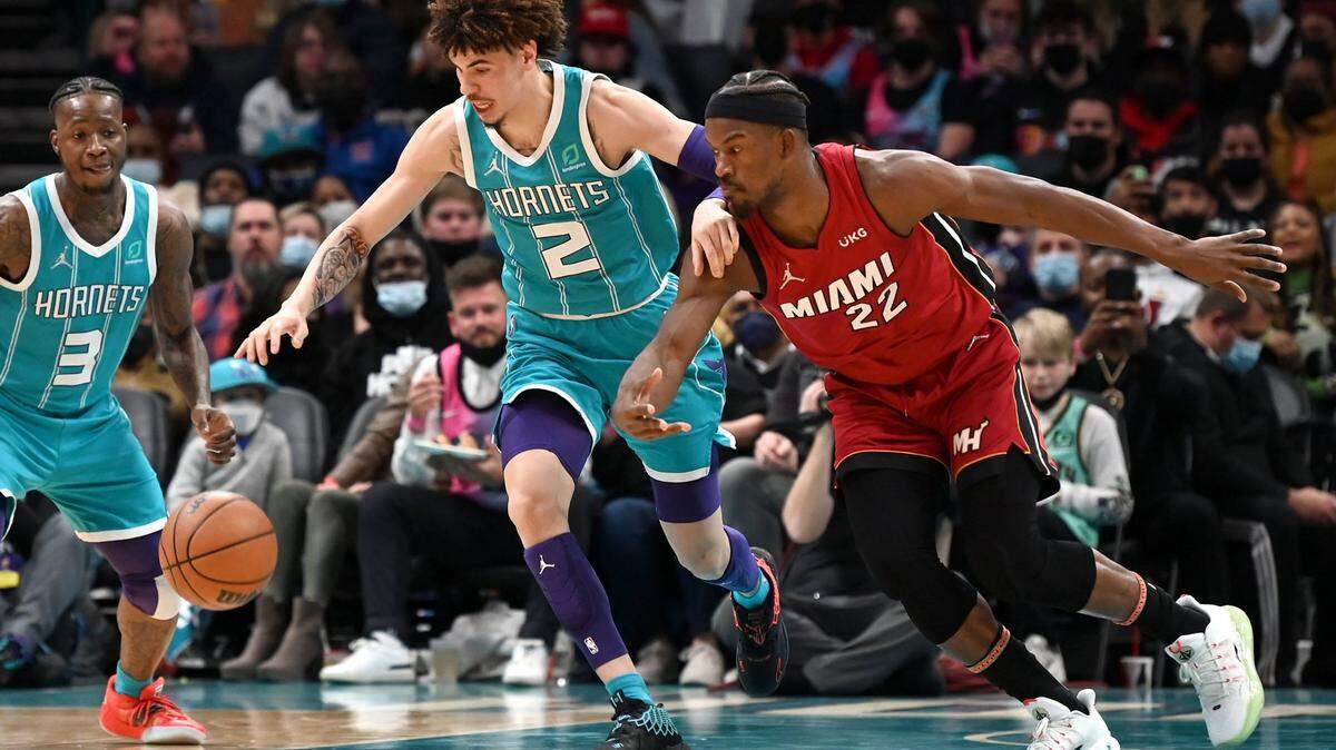 Charlotte Hornets guard LaMelo Ball, left, battles Miami Heat guard Jimmy Butler, right, for control of the ball during first half action on Saturday, February 5, 2022 at Spectrum Center in Charlotte, NC.