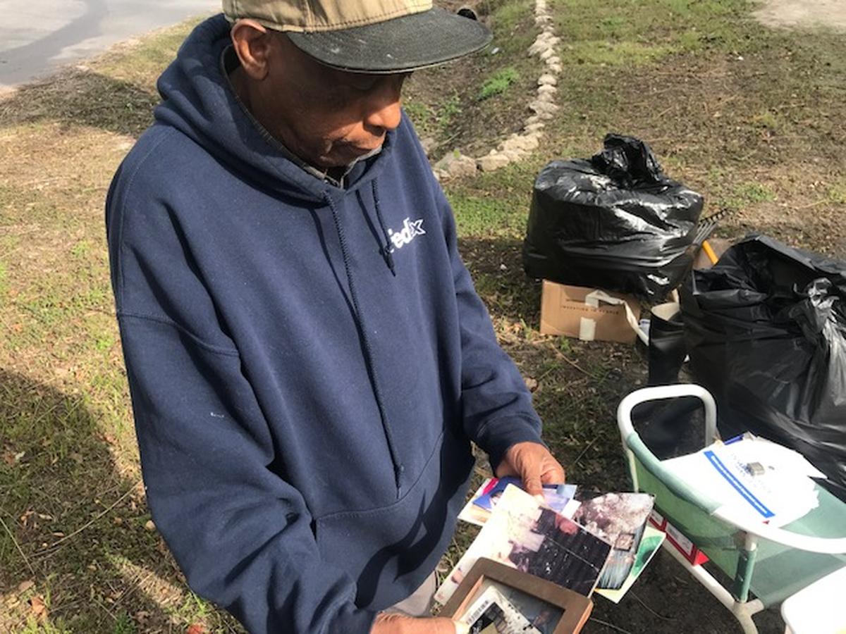 Robert Douglas Jr. looks at photographs of his grandkids that were damaged in the floodwaters of Hurricane Florence. His house was mucked and gutted by Americorps and United Way on Tuesday in partnership with Panthers defensive end Julius Peppers.